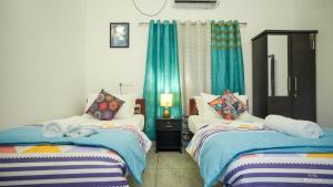two beds in a room with blue curtains at VILLA MANTRAA in Varkala +48 photos