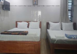 two beds with white pillows and avertisement at Biển Ngọc Homestay - Ngay sát biển Phan Rang in Bắc Sớn