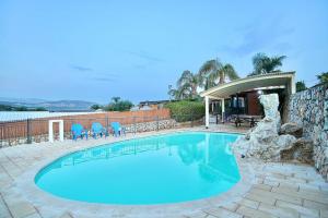 a swimming pool with blue chairs and a stone wall at אצולת הגליל in Kallanit