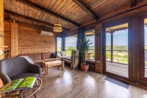 a living room with a couch and chairs and windows at Zalaidill Wellness Vendégház in Nagybakónak