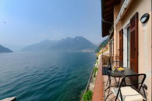 a balcony with a table and a view of the water at Grace Suite with Jacuzzi Wonderful Lakefront View in Colonno