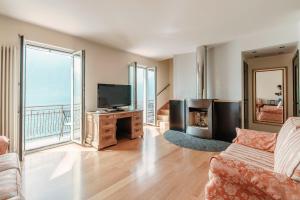 a living room with a couch and a television at Grace Suite with Jacuzzi Wonderful Lakefront View in Colonno
