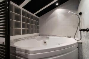a white bath tub in a white tiled bathroom at Grace Suite with Jacuzzi Wonderful Lakefront View in Colonno +16 photos