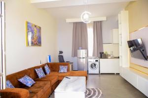 a living room with a brown couch and a kitchen at Spea Apartments in Mbarara
