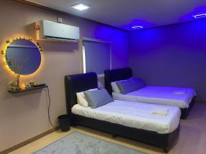a purple room with two beds and a mirror at Inapan eynaman in Kangar