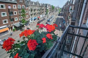 a balcony with red flowers on a city street at Hotel Larende in Amsterdam