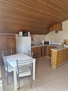a kitchen with a table and chairs and a refrigerator at Casa Amarela in Zambujeira do Mar