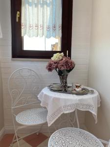 a table with a vase of flowers and a window at Petitti Maison in Motta Montecorvino +7 photos