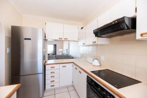 a kitchen with white cabinets and a stainless steel refrigerator at Panoramic Ocean View 2 bed w 24 hour Power Inverter, Blouberg, 28 Malata in Bloubergstrand