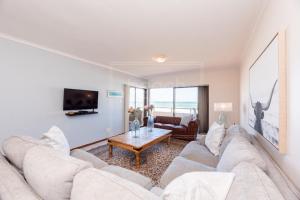 a living room with a couch and a table at Panoramic Ocean View 2 bed w 24 hour Power Inverter, Blouberg, 28 Malata in Bloubergstrand +19 photos
