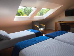 Una habitación de hotel con dos camas y una ventana. en Hotel O Noso Portosin, en Portosín 99 fotos más