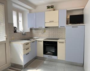 a white kitchen with white cabinets and a refrigerator at Il Glicine - Monolocale a due passi dal centro in Urbino +10 photos