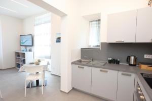 a kitchen with white cabinets and a white table and a table and chair at Verdemare relax & rooms in Sestri Levante