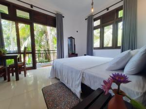 a bedroom with a bed and a balcony with windows at Turtle Point Homestay Seaview 2 - BB, Fast Wi-Fi, AC in Dickwella