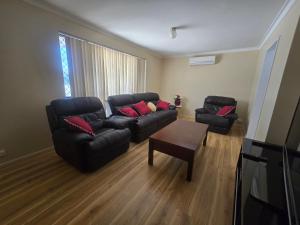 a living room with a black couch and a table at Advantage house in Kelmscott