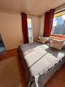 a bedroom with a bed with red curtains and a window at Casa Cypresses in Temuco +9 photos