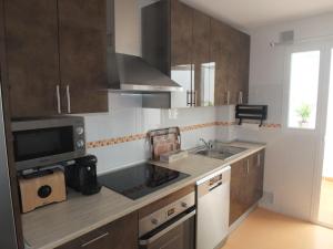 uma cozinha com armários de madeira, um lavatório e um micro-ondas em Apartamento Mijas Costa, Las Lagunas em Mijas Costa