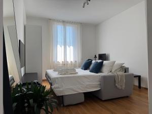 a white bedroom with a bed with blue pillows at Comfort Stay Legnano - Appartamento di 85m2 con 2 bagni, Smart TV, WiFi ultra veloce e angolo lavoro, perfetto per visitare Milano in relax in Legnano