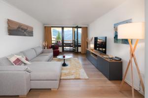 a living room with a couch and a tv at Wohnung Edelweiss Direkt In 4 Sterne Hotel in Beatenberg