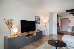 a living room with a flat screen tv on a cabinet at Wohnung Edelweiss Direkt In 4 Sterne Hotel in Beatenberg