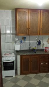 a kitchen with wooden cabinets and a stove top oven at Hospedaria - Hostel Gamboa in Angra dos Reis
