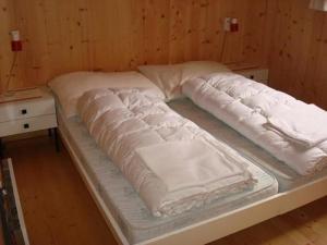 a bed with white sheets on top of it at Chalet Bärli in Fiesch