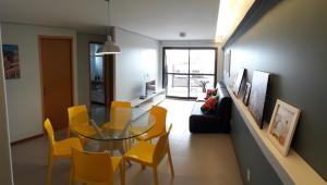 a living room with a glass table and yellow chairs at Apartamento na Ponta Verde in Maceió