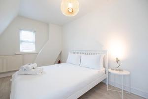 een witte slaapkamer met een wit bed en een lamp bij Gorleston Beach House by Leap Escapes in Gorleston-on-Sea