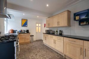 een grote keuken met houten kasten en zwarte aanrechtbladen bij Gorleston Beach House by Leap Escapes in Gorleston-on-Sea