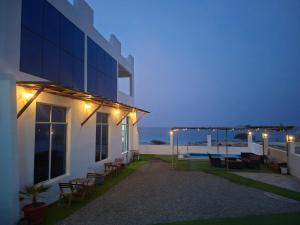 a building with a patio with chairs and lights at Wadi shab guest house in Ţīwī
