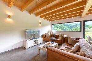 ein Wohnzimmer mit Sofa und Fernseher in der Unterkunft Villa Alésia - Jacuzzi et vue montagnes, environnement apaisant in Saint-Eustache