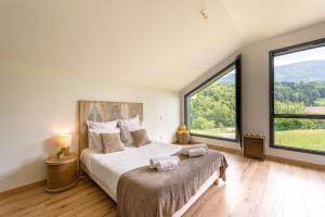 Schlafzimmer mit einem großen Bett und großen Fenstern in der Unterkunft Villa Alésia - Jacuzzi et vue montagnes, environnement apaisant in Saint-Eustache