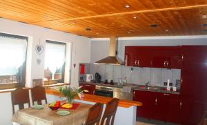 a kitchen with red cabinets and a wooden ceiling at Ferienwohnung im Bergischen Land in Waldbröl