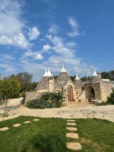 an old stone building with a door and grass at Trullo Amalia con piscina privata in Latiano