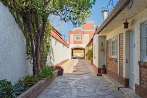an alleyway between two buildings with a tree at Complejo Abaurrea in Mendoza