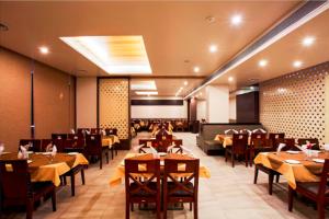 a restaurant with tables and chairs in a room at Hotel Rasika in Kolhapur