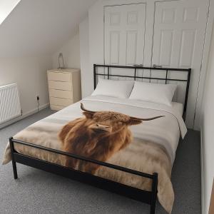 a bed with a painting of a cow on it at The Old School-Annexe in Scotlandwell +8 photos