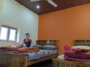 ein kleines Mädchen sitzt auf einem Bett in einem Zimmer in der Unterkunft TungaTeera Homestay in Sringeri + 2 Fotos