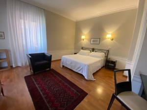 a bedroom with a white bed and a black chair at Hotel Lancelot in Rome