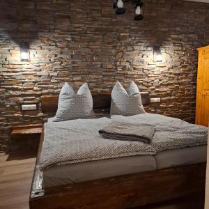 a bedroom with a bed with pillows and a brick wall at Kleine Auszeit Im Alten Huthaus in Brand-Erbisdorf