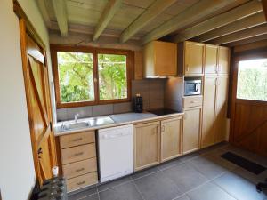 a kitchen with wooden cabinets and a sink and a window at Comfortable Home with Sauna in Flobecq