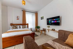 a bedroom with a bed and a tv and a couch at Lorien Homes in Nairobi