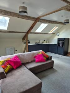 a living room with a brown couch with pink pillows at Priors Marston in Priors Marston