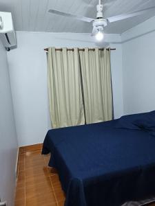 Un dormitorio con una cama azul y un ventilador de techo. en AlojamientolaFamilia, en Puerto Iguazú
