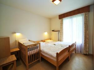 ein Schlafzimmer mit einem Kinderbett vor einem Fenster in der Unterkunft Bright Chalet with Terrace in Randogne