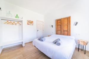a white bedroom with a bed and a wooden floor at Casa Rural Entre Almendros in El Toboso