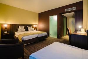 una habitación de hotel con dos camas y un escritorio en Badam Hotel, en Ganja