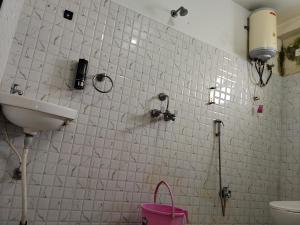パトナーにあるHotel bihanの洗面台とピンクのバッグが置かれた白いタイル張りのバスルーム +8枚の写真