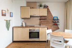 a kitchen with wooden cabinets and a table with white chairs at Apartamentai NEMUNAS in Pervalka