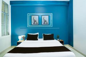 a blue bedroom with a white bed and two pictures on the wall at Hotel O SS in Jaipur